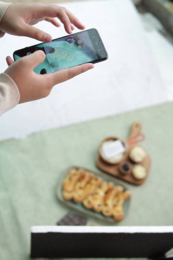 Genç bir kadın akıllı telefonunun fotoğrafını çekiyor.