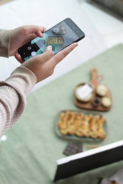 Restoranda elinde akıllı telefon tutan bir kadın.