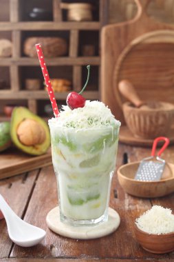 Bir bardak hindistan cevizi kokteyli ve buzlu beyaz bir masa ve bir fincan çay.