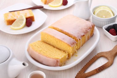 Portakal reçeli ve ahşap bir masada limon dilimleri olan bir pasta parçasının yakın plan fotoğrafı.