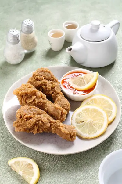 fried chicken with lemon and green tea on plate
