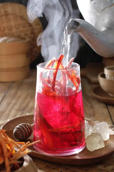 red hot drink with spices and ice on a wooden table