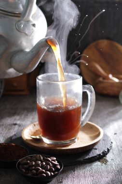 Siyah arka planda beyaz bardakta sade sıcak kahve.