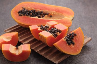 Tahta kesim tahtasının üzerinde dilimlenmiş tohumlarla taze papaya meyveleri