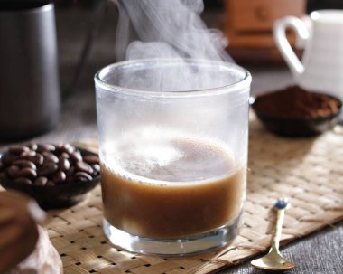 Tahta arka planda kahve çekirdekleri olan bir bardak kahve.