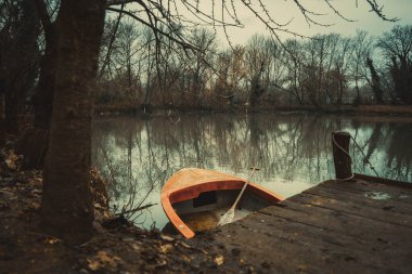 Sonbahar ormanındaki nehirde yansıması olan ahşap iskele.