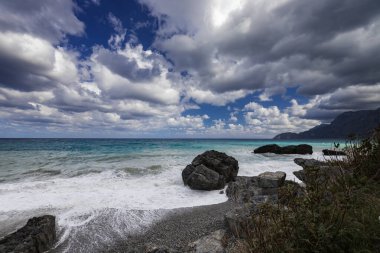 Yunan adası Evia kıyısı ve güneşli bir günde güzel deniz manzarası fantastik bulutlarla mavi gökyüzü, yatay çerçeve