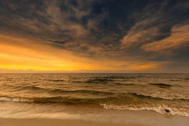 Gün batımında Polonya 'da, Baltık Denizi' nin üzerinde gökyüzüne bakan kumsal manzarası.