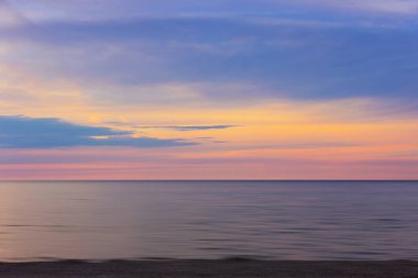 Gün batımında Polonya 'da, Baltık Denizi' nin üzerinde gökyüzüne bakan kumsal manzarası.