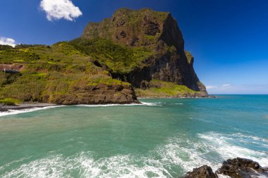 Madeira 'da (Porto da Cruz) güneşli bir günde dalgalarla kayalık kıyı ve mavi Atlantik Okyanusu manzarası, tasarımın için arka plan veya duvar kağıdı