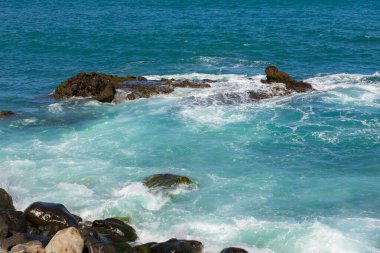 Madeira 'da (Porto da Cruz) güneşli bir günde dalgalarla kayalık kıyı ve mavi Atlantik Okyanusu manzarası, tasarımın için arka plan veya duvar kağıdı