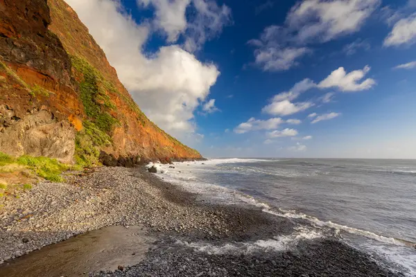 Arkasında güzel bir gökyüzü olan kayalık bir plaj.