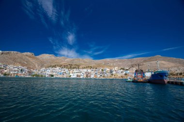 Açık mavi gökyüzü altında tekne ve binaların olduğu liman sahnesi, Kalymnos, Yunanistan