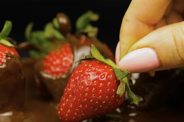 手拿着黑色背景的新鲜草莓 — 图库照片