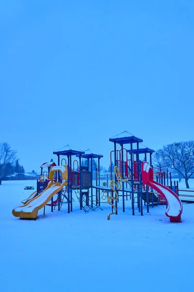 Explore the magic of a small park blanketed in snow, where swings and playground equipment are adorned in white, creating a magical and serene winter scene.