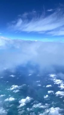 Air Canada uçuşu, kanat, motor ve bulut hareketlerini bir pencere oturağından yakalıyor. Aşağıda, mavi ve yeşil tonlarda toprak ve denizin çarpıcı manzarası görülebilir. Seyahat içeriği için ideal.