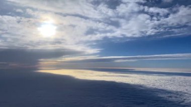 Air Canada uçuşu, kanat, motor ve bulut hareketlerini bir pencere oturağından yakalıyor. Aşağıda, mavi ve yeşil tonlarda toprak ve denizin çarpıcı manzarası görülebilir. Seyahat içeriği için ideal.