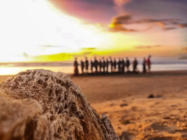 Gün batımında sahilde oturan bir grup insan.