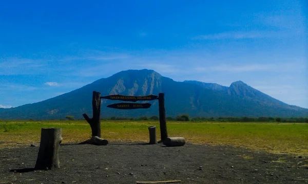 Güneşli bir günde mavi gökyüzü dağlarıyla çayır arka planında turist panosu