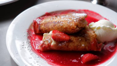 Crepes filled with cream cheese and sultanas, served with raspberry coulis and vanilla ice cream.