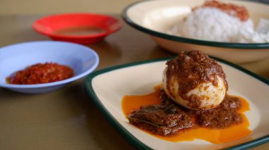 Rendang Telur or Rendang Egg on a plate with Nasi Uduk.