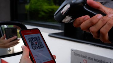 Bir kasiyer, açık hava sinemasında akıllı bir telefondan QR kodunu tarıyor. Shopee Pay ile peşin ödeme. Jakarta, 29 Mart 2022.