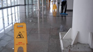 Sarı alarm, MRT istasyonunda ıslak zemin tabelası tehlike görüntüsü, açık alanda temizlik yapılıyor. Jakarta, 9 Nisan 2022.