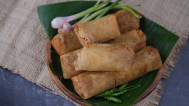 Lumpia Semarang on wooden plate with spring onion and green chilli. Indonesia food.