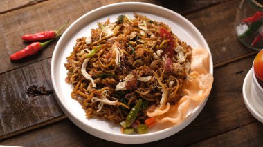 fried noodles with chicken meat and crackers isolated on wooden table, top view