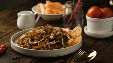 fried noodles with chicken meat and crackers isolated on wooden table, top view