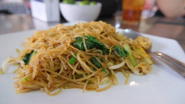 Fried noodles on a plate on wooden table.