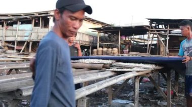 Öğleden sonra iki balıkçı tuzlu balığı örter. Kuzey Jakarta 'dan Cilincing' e. 19 Temmuz 2022.