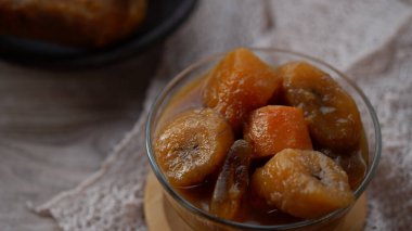 Beyaz bir masadaki bir kasede muz kompostosu veya Kolak Pisang muz, tatlı patates ve hindistan cevizi sütü, pandan ve palmiye şekeriyle pişirilmiş fro..
