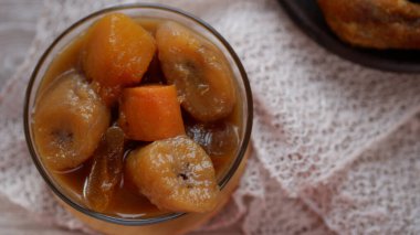 Beyaz bir masadaki bir kasede muz kompostosu veya Kolak Pisang muz, tatlı patates ve hindistan cevizi sütü, pandan ve palmiye şekeriyle pişirilmiş fro..