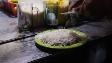 Bir sokak satıcısında rendelenmiş peynir ve sütle ızgara muz hazırlıyorum. Pisang Bakar.