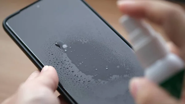 スマートフォンの画面を液体スプレーで掃除 — ストック写真
