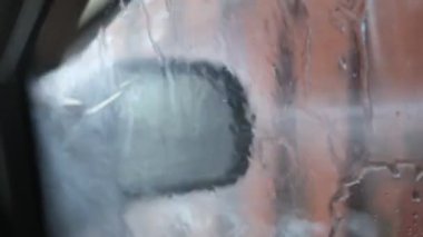 Yıkanan araba, araba yıkama yerindeki arabanın içinden görünen suyla dolu.