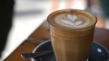 Tahta bir masanın köşesinde kaşık ile bir fincan kahve.