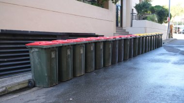 Kırmızı kapaklı ve sarı kapaklı çöp tenekesi konut alanında. Sydney, 30 Mayıs 2023
