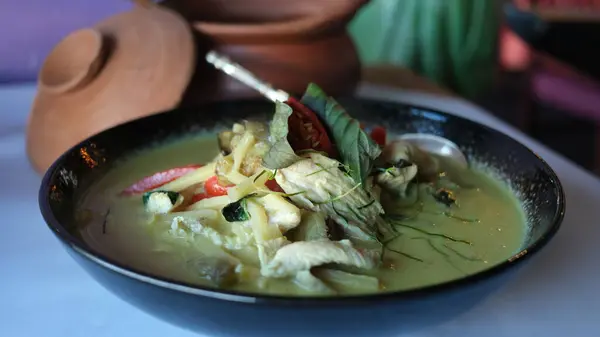 stock image Thai chicken green curry on a black plate on a table.