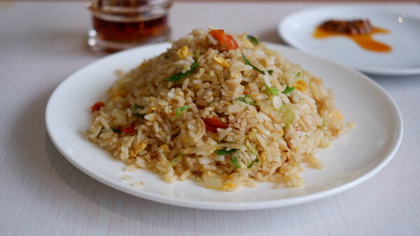 Ян Чоу жарил рис на белой тарелке с маслом чили. Китайская еда.