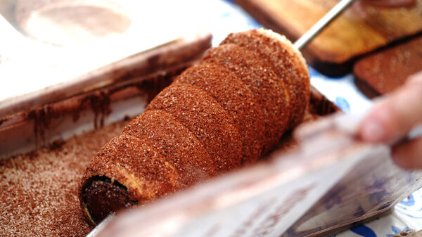 Kurtosh is made from yeast dough, of which a strip is spun and then wrapped around a truncated coneshaped baking spit, and rolled in granulated sugar. It is roasted over charcoal with melted butter, until its surface cooks to a golden-brown color.