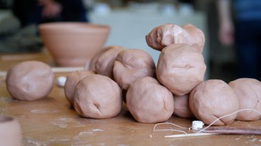 Çamur, fırlatma çarkında seramik çömlek yapmak için masaya yığılmış..