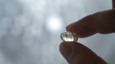 Parmak yüksek dozda yumuşak jel tutar 7000 vitamin D3 kapsülü.