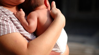 Bir kadın dışarıda güneşlenmek için yeni doğmuş bir bebeği taşıyor..