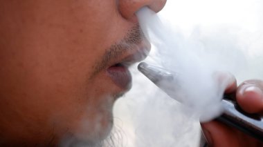 Burnundan duman çıkan bir e-sigarayı buharlaştıran bir adam. Jakarta, 11 Ekim 2024.