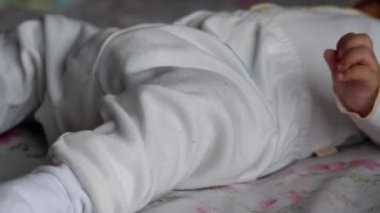 Yatağa uzanmış pantolon ve çorap giyen bir bebek..