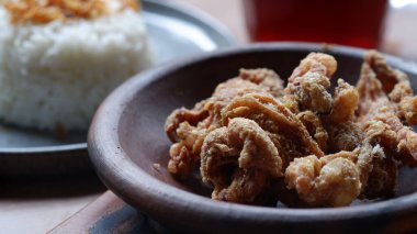 Kil tabakta kızarmış tavuk derisi ve masada pilav..