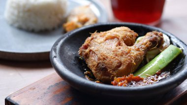 Kil tabakta sambal ve salatalıklı geleneksel Endonezya kızarmış tavuğu, pirinç ve buzlu çayla servis edilir..