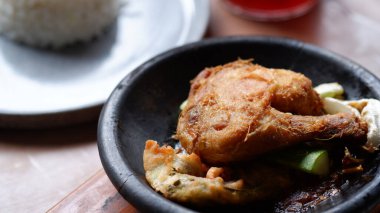 Kil tabakta sambal ve salatalıklı geleneksel Endonezya kızarmış tavuğu, pirinç ve buzlu çayla servis edilir..